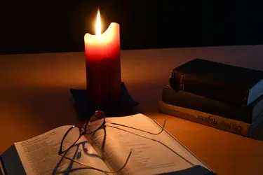 Lesen in der Bibel, mit Lesebrille, Kerzenschein
